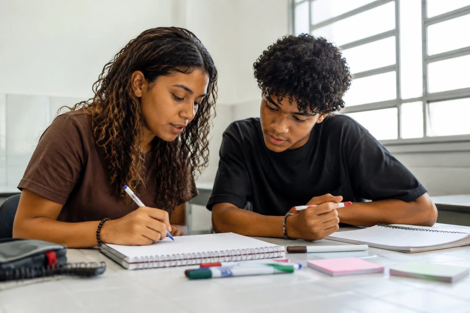 Dois estudantes preparando um debate com cadernos e marcadores